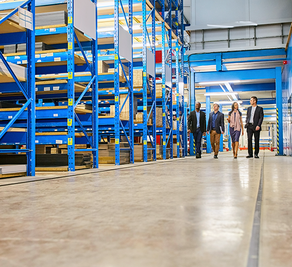Four workers walking in a storage warehouse