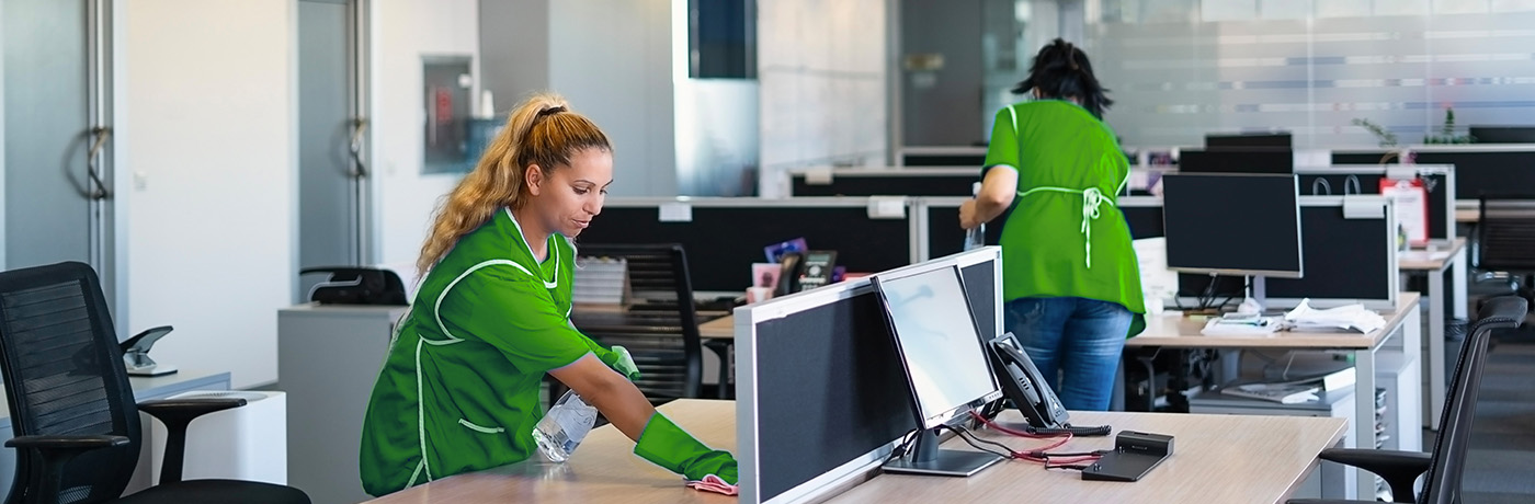 Three commercial cleaners cleaning around a desk