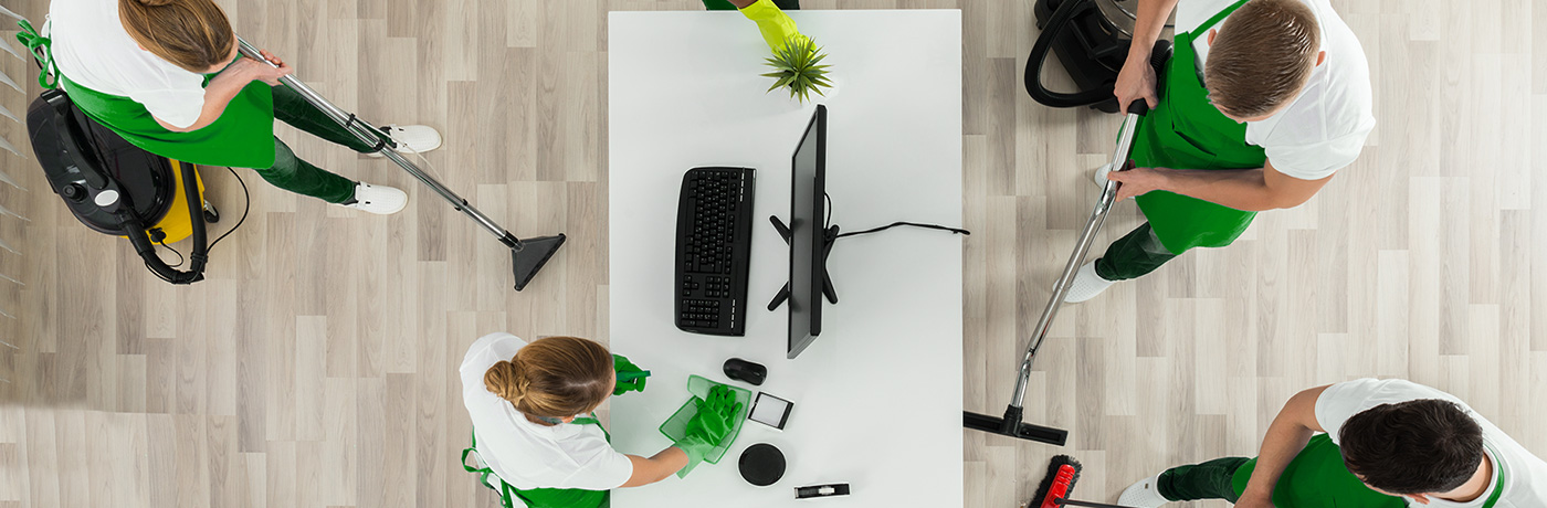 Three commercial cleaners cleaning around a desk