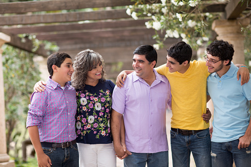 Family of five smiling in a garden setting, wearing casual clothes, with arms around each other.
