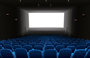 Empty movie theater with blue seats facing a blank cinema screen.