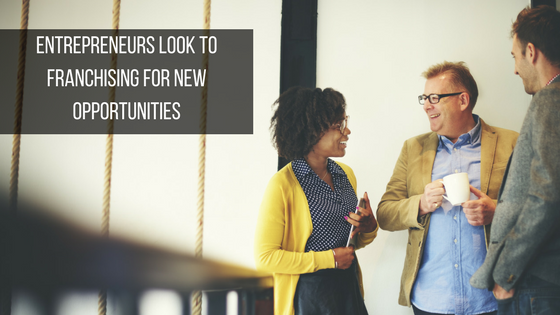 Three people chatting and smiling with a text overlay: "Entrepreneurs look to franchising for new opportunities."