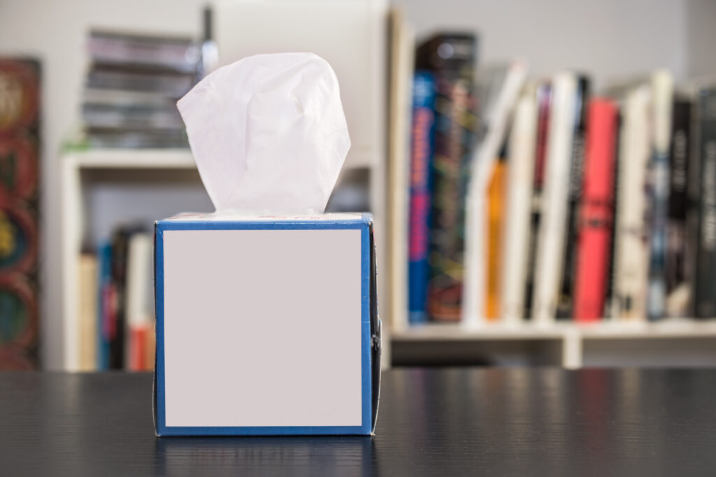 Tissue box on a table with blurred bookshelves in the background.