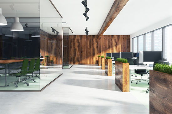 Modern open-plan office with wooden accents, glass-walled meeting room, and plants on desks, illuminated by natural light.