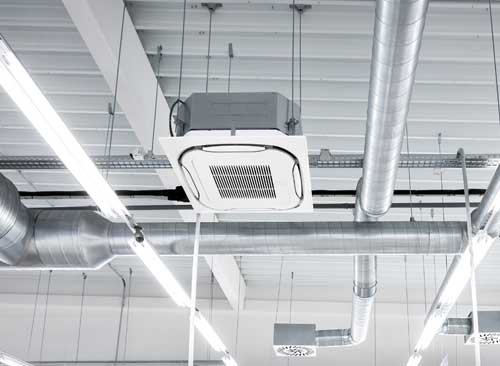Ceiling-mounted air conditioning and ductwork in a commercial space with fluorescent lighting.