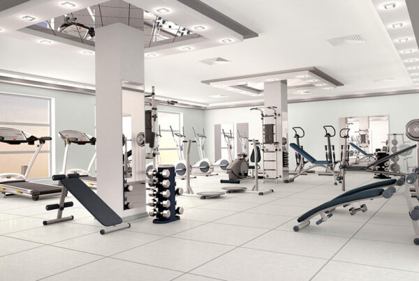 Modern gym with exercise equipment, including treadmills, weight machines, and free weights, in a bright, spacious room.