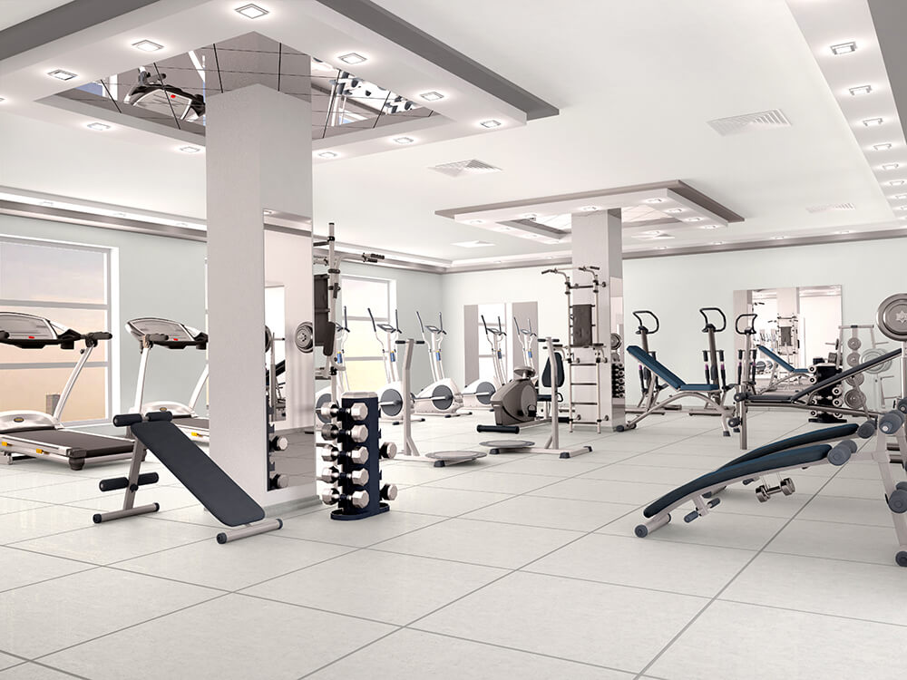Modern gym with exercise equipment, including treadmills, weight machines, and free weights, in a bright, spacious room.