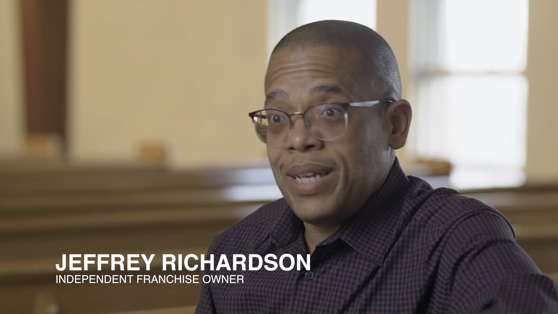 Man speaking in an interview, wearing glasses and a patterned shirt, seated indoors. Text reads: "Jeffrey Richardson, Indepen