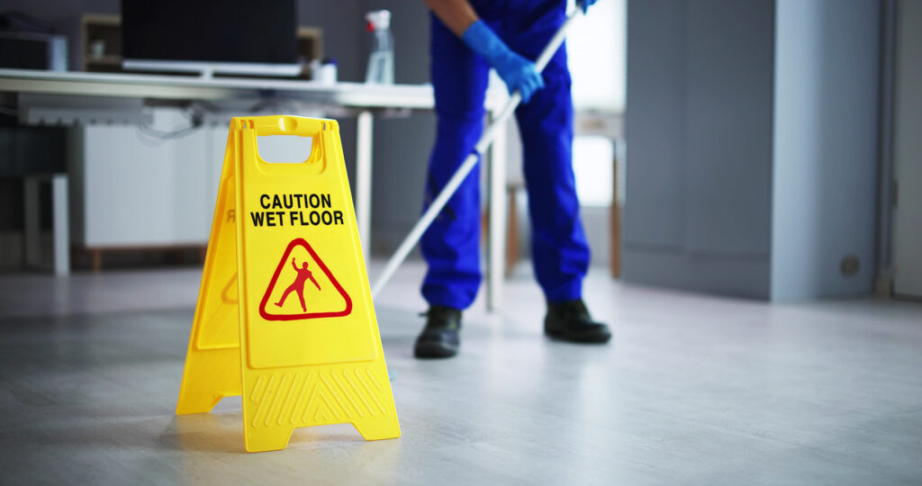 Caution Wet Floor Sign while a person mops
