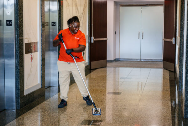 A female commercial cleaner mopping the lobby of an office building.